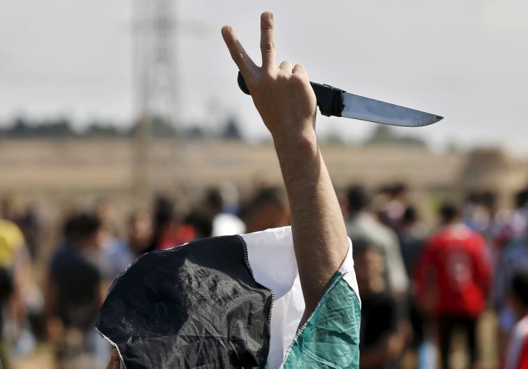 A masked Palestinian protester holds a knife during a protest near the Israeli border fence in northeast Gaza A masked Palestinian protester holds a knife during a protest near the Israeli border fence in northeast Gaza