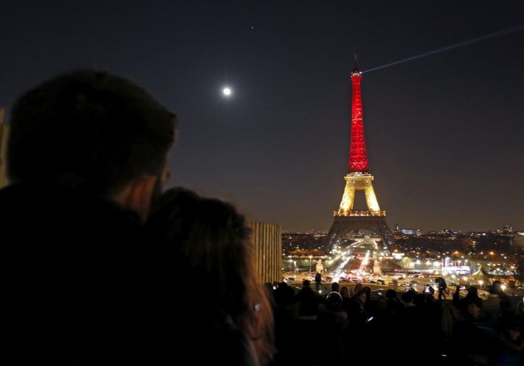 A couple looks at the Eiffel Tower lit up in the colors of the Belgian flag in Paris A couple looks at the Eiffel Tower lit up in the colors of the Belgian flag in Paris